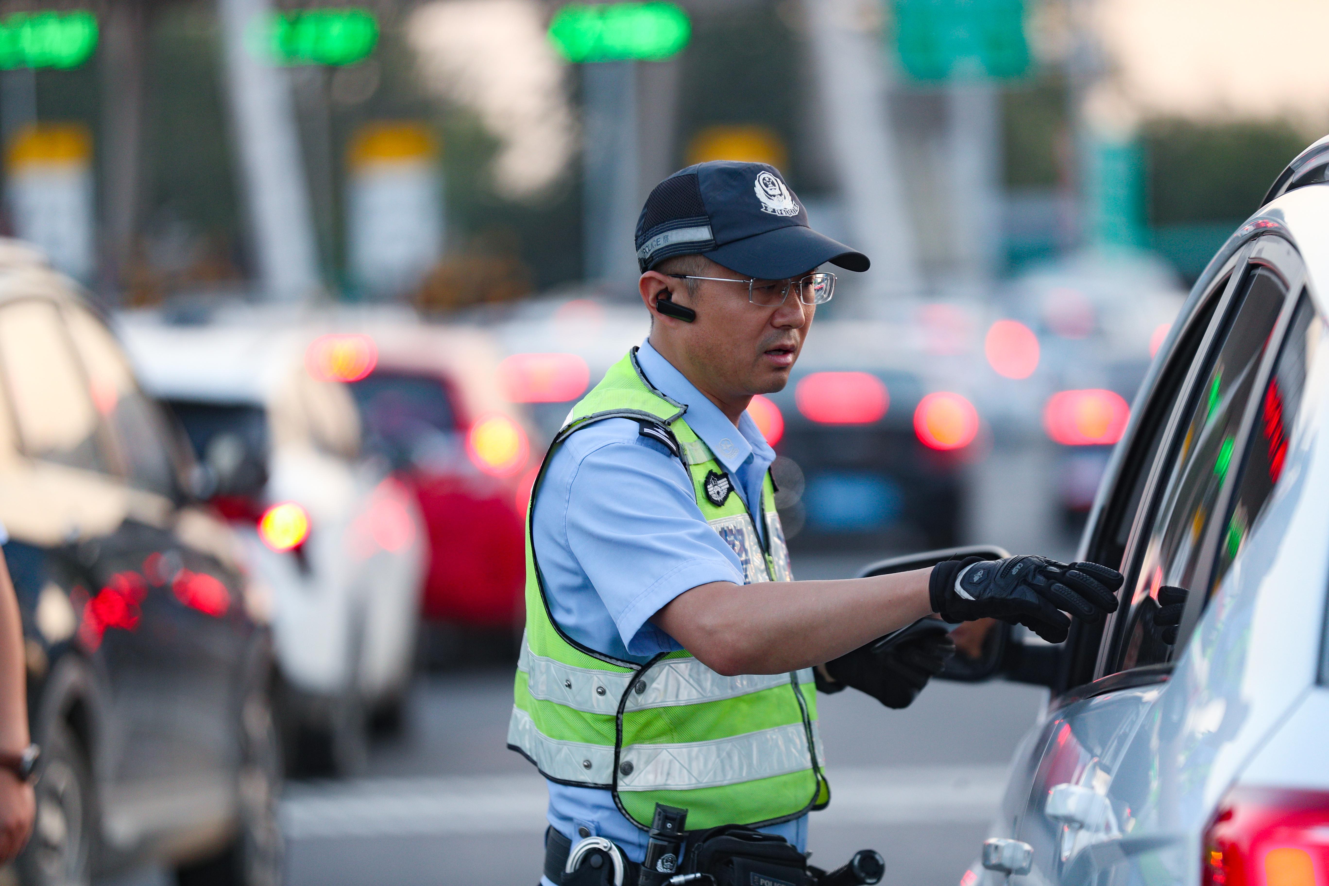炎炎夏日，許俊富在高速公路出口的車流中提示過往司機注意安全.jpg